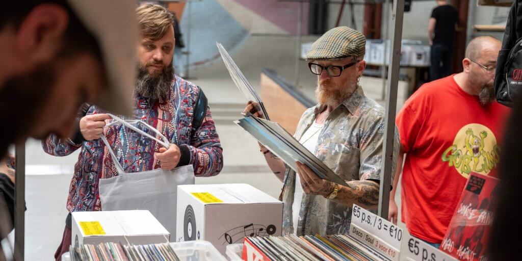 Bezoekers die aan het winkelen zijn in de vinylmarkt met kraampjes in de skatehal van Pier15.
